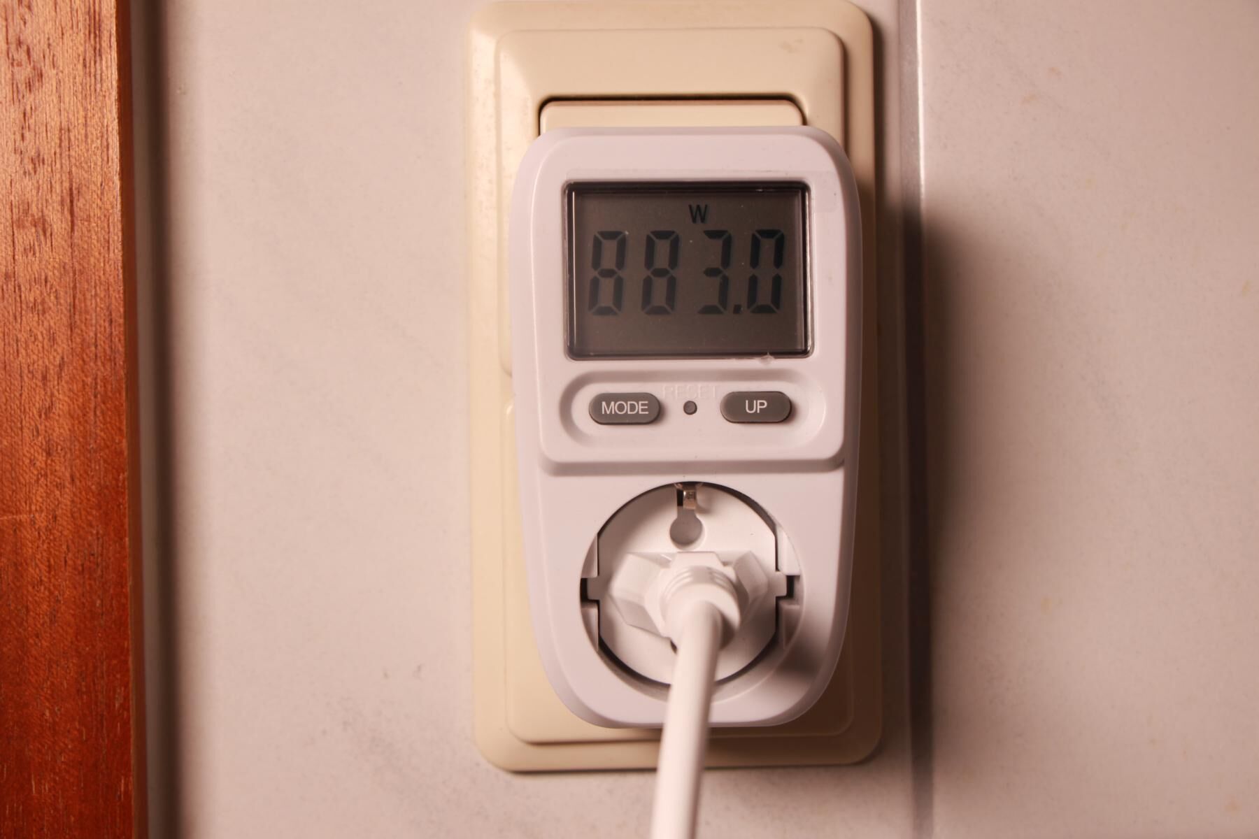 Eine Strommess-Steckdose ist eingesteckt und zeigt 883 Watt an.